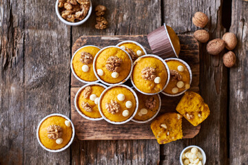 Pumpkin muffins with white chocolate and walnuts. Side view, wooden background.
