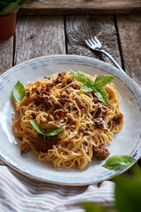 Spaghetti with bolognese sauce and basil. Side view, wooden background.