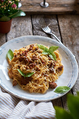 Spaghetti with bolognese sauce and basil. Side view, wooden background.
