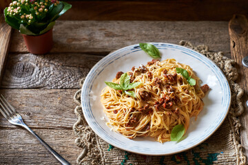 Spaghetti with bolognese sauce and basil. Side view, horizontally, wood background.