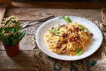 Spaghetti with bolognese sauce and basil. Side view, horizontally, wood background.