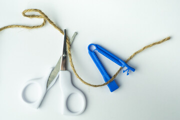sterile scissors and umbilical cord clamp with a rope on white background. Birth at home, cutting...