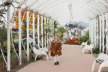 happy little child, girl laughs and plays in the autumn in the amusement park walks in nature
