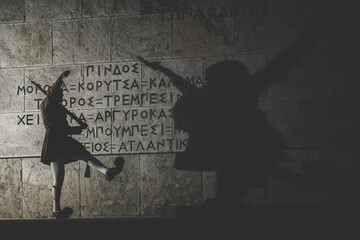 Silhouette of a guardian and his shade on an ancient wall with a greek note