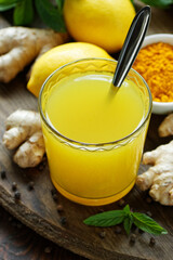 Immune booster antivirus drink, turmeric with ginger, lemon, mint and spices hot winter tea on wooden rustic background, closeup, natural medicine and naturopathy concept
