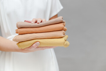 cropped image of smiling seamstress holding stack of colored fabric