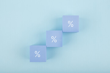 Toy blocks as a ladder with percentage sign on bright pastel blue background