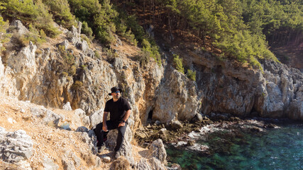 A man in black clothes sits on the rocks