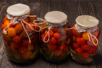 jars of pickled tomatoes on a wooden background