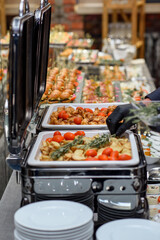 A set of canapes and snack at a banquet with white table. Slices of tomato, olive, cheese, bread and fish on food stand