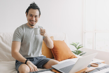 Obraz na płótnie Canvas Happy creative asian man work on laptop in his home office apartment.