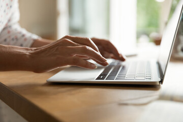 Hands of woman typing on keyboard, using app on laptop. Freelance employee working from home....