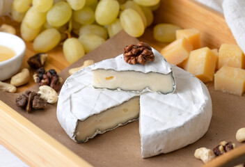 Brie cheese with nuts and grapes on craft paper