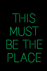 Fototapeta na wymiar This must be the place green neon sign isolated against black background