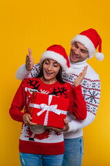 Fototapeta premium Close up photo of beautiful happy and excited young couple in love in Christmas clothes with gift boxes in hands while they celebrating New Year and giving presents yo each other