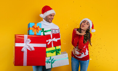 Excited modern couple in love with many colorful gift boxes in hands while they celebrating Christmas and New Year and having fun