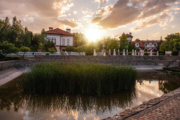 Obraz premium Panoramic view of the cottage village by the pond with green reeds at sunset. Life outside the city