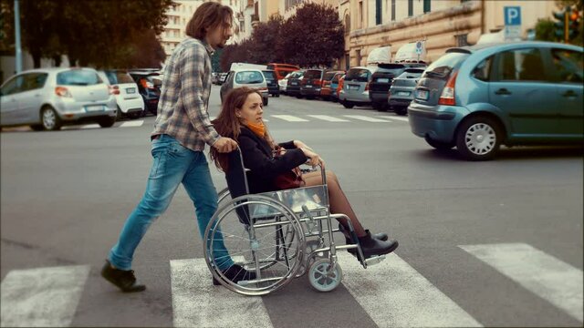 person who uses a wheelchair - man crosses the street pushing her girlfriend