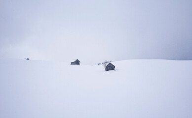Traditionelle Almhütte aus Holz in kalter verschneiter Winternatur auf einer Alpe in den...