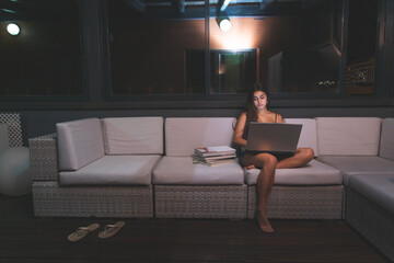 Young caucasian woman night study at terrace's sofa. Madrid, Spain.