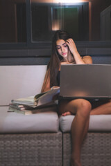 Young caucasian woman night study at terrace's sofa. Madrid, Spain.