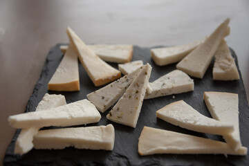 Slices of traditional spanish Manchego cheese on black plate. Selective focus. 