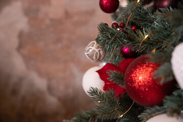 Closeup photo of festive balls on fir tree in living room. white, red Christmas decorations hanging on tree.ackground for winter celebrations with decorated Christmas tree