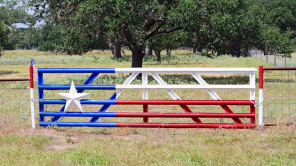 Fototapeta na wymiar Texas Star on a Fence in the field with Texas Flag painted on metal fence with big oak tree in background.