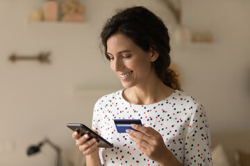 Happy female customer using banking app on mobile phone for quick payment by credit card. Woman...