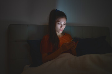 Woman sleeping using phone in bed staying up late at night reducing her sleep time which is bad for mental health and depression. - obrazy, fototapety, plakaty
