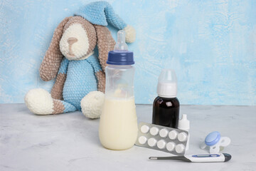 Breastfeeding and pills .Medication and lactation. Milk, children's toy, thermometer, syrop, pills and pacifier on blue background. Viruses. Copyspace
