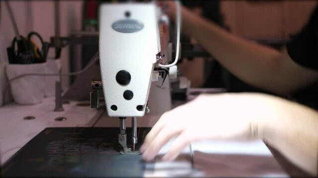 A person operating the sewing machine for book binding at a traditional printing shop shot in 4K