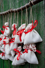 Christmas advent calendar hangs on a green wooden wall. Gift bags are secured with soutache rope on...