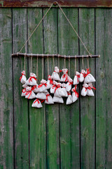Christmas advent calendar hangs on a green wooden wall. Gift bags are secured with soutache rope on...