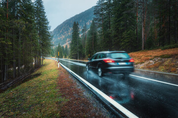 Blurred car in motion on the road in autumn forest in rain. Perfect asphalt mountain road in...