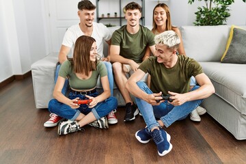 Group of young friends smiling happy playing video game at home.