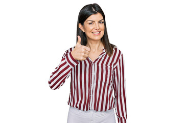 Beautiful brunette woman wearing striped shirt doing happy thumbs up gesture with hand. approving expression looking at the camera showing success.