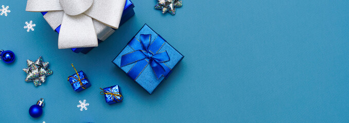 Blue christmas background of gift box and snowflake decorations and balls of blue and silver color. Winter holidays concept. Flat lay, top view, copy space.
