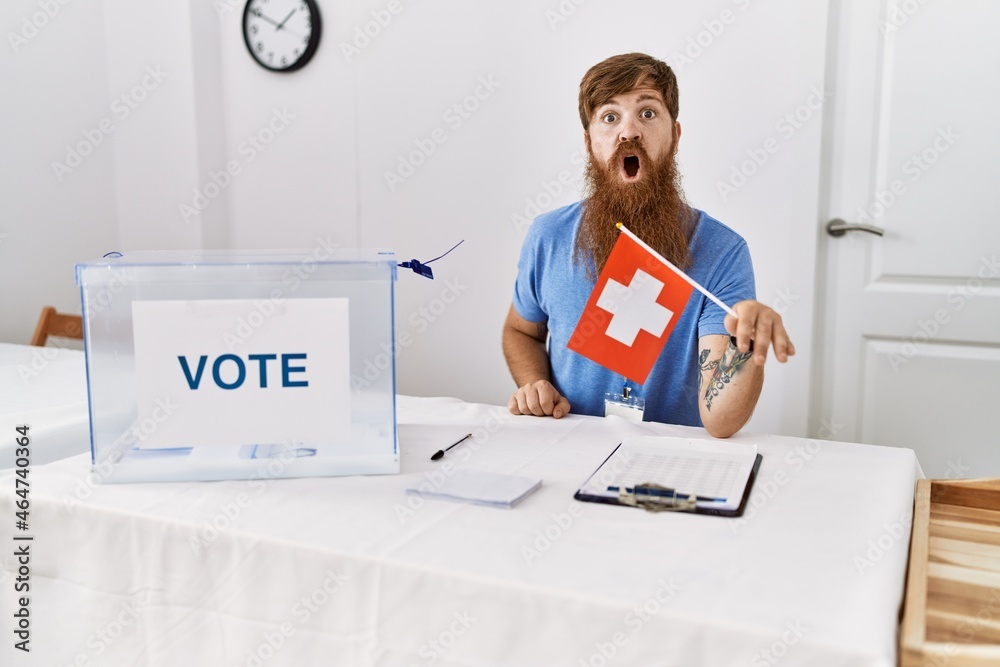 Wall mural caucasian man with long beard at political campaign election holding swiss flag scared and amazed wi