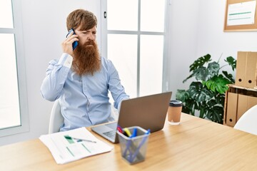 Young irish businessman with serious expression talking on the smartphone at the office.