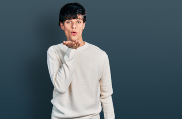 Handsome hipster young man wearing casual winter sweater looking at the camera blowing a kiss with hand on air being lovely and sexy. love expression.