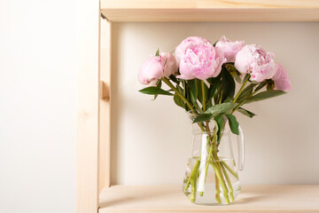 bouquet of fresh pink peonies in a glass vase on a shelf. holiday and gifts concept