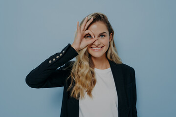 Blonde caucasian female looking through okay sign gesture