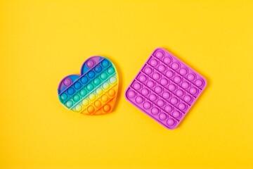 Top view Pop it fidget toy on a empty yellow background. Multicolored antistress toy flat lay