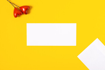 top view love letter, white envelope and card with red hearts on yellow background. white letter with copy space flat lay