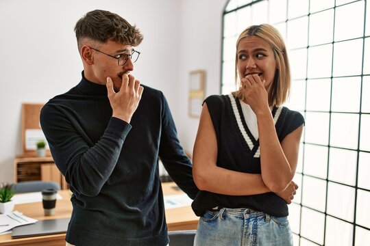 Two beautiful business workers wearing business style standing at the office looking stressed and nervous with hands on mouth biting nails. anxiety problem.