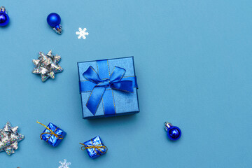 Blue christmas background of gift box and snowflake decorations and balls of blue and silver color. Winter holidays concept. Flat lay, top view, copy space.