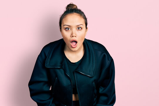 Young hispanic girl wearing sportswear afraid and shocked with surprise and amazed expression, fear and excited face.