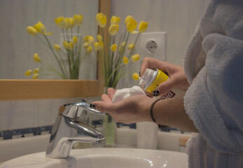 Close up young man hand in bathrobe picking up shaving foam in apartment bathroom. Beauty Home Spa Concept.
