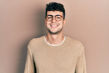 Young hispanic man wearing casual clothes and glasses with a happy and cool smile on face. lucky person.
